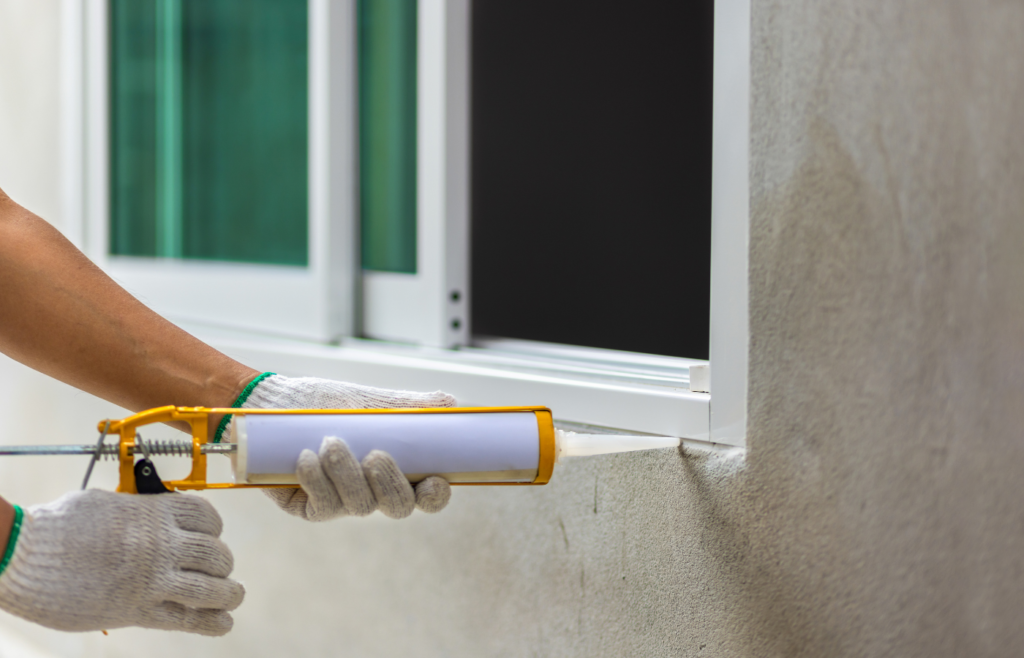 Construction worker using silicone sealant caulk the outside window